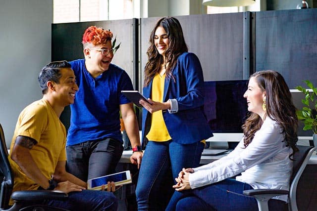 Diverse group of young professionals collaborating and smiling during a team meeting in a modern office environment.